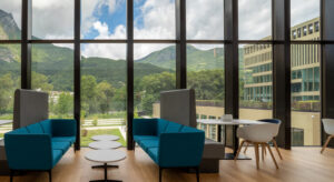 Expansive view of outdoor mountains through large glass windows of a lobby.