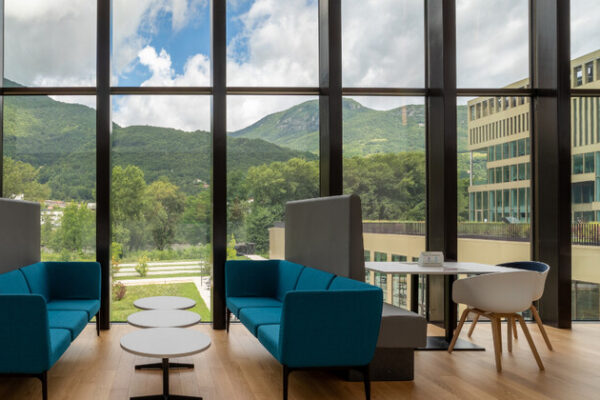 Electrochromic Windows Expansive view of outdoor mountains through large glass windows of a lobby.
